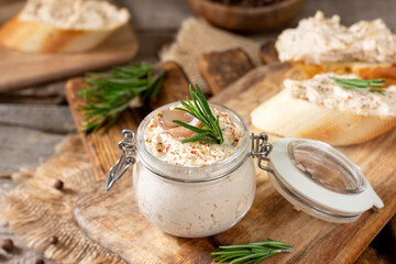 Chicken pate in a glass jar on the brown wooden kitchen table. Homemade chicken fillet pate with...