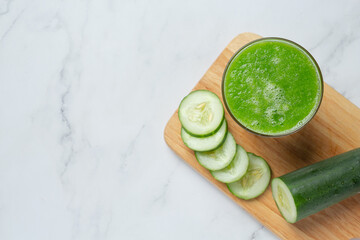 Glass of fresh cucumber juice on marble background