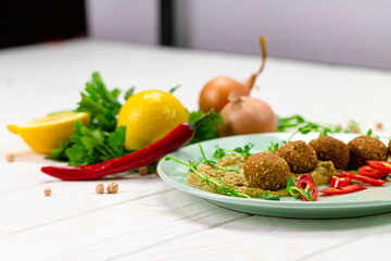 Traditional homemade falafel with hummus, chili pepper and microgreen shoots. Falafel with ingredients - chickpea, parsley, lemon, onion, chili pepper. Arabic, vegan food concept