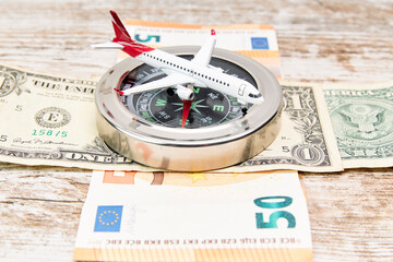Airplane on a compass and some dollar and euro bills. Vacation concept