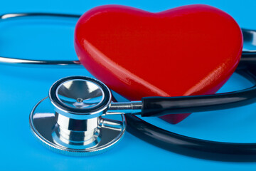 Stethoscope and red heart on a blue background close-up.