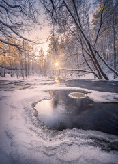 Scenic winter landscape with flowing river and morning light in Finland. Snowy trees. - 410074204