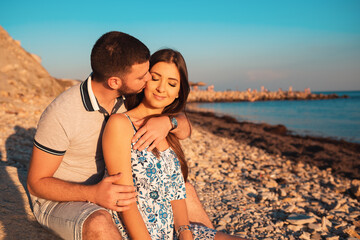 Honeymoon. Man gently kissing a woman. Sea and sky on the background