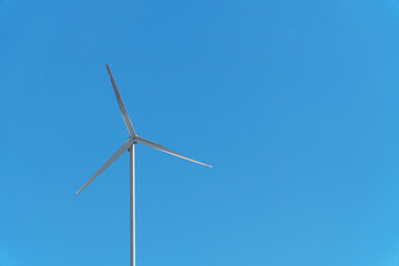 A small wind white turbine with a sky as a background.