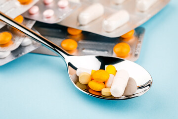 The tablets are randomly scattered around the spoon on a blue background