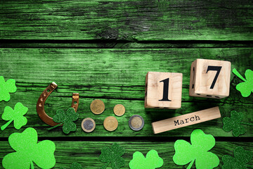 Flat lay composition with clover leaves and block calendar on green wooden table, space for text....