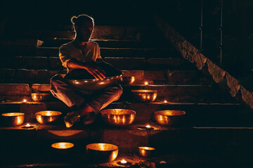 Young musician playing on plays on authentic singing Tibetan bowls urban street