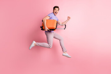 Fototapeta na wymiar Full length body size photo of happy man jumping high with baggage laughing running to airport isolated on pastel pink color background
