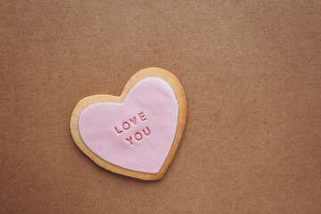 Obraz premium Heart shaped cookies with pink glaze and the inscription: «love you» located on a craft paper background with space for your text..Valentine's Day gifts