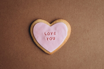 Heart shaped cookies with pink glaze and the inscription: &laquo;love you&raquo; located on a craft paper background with space for your text..Valentine's Day gifts