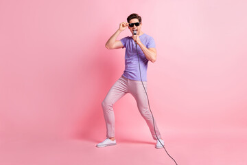 Full length body size photo of male singer performing on stage wearing sunglass isolated on pastel pink color background