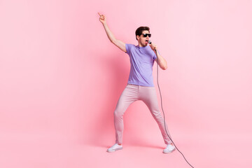 Full length photo of young excited guy enjoy concert sing pop song microphone star isolated over pastel color background
