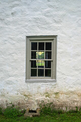 Fototapeta na wymiar Colonial stone house with blue twelve-pane window exterior