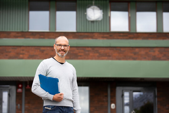 Smiling teacher in front of school