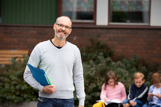 Smiling teacher in front of school