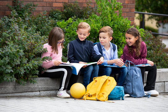 Children looking at school books in front of school building