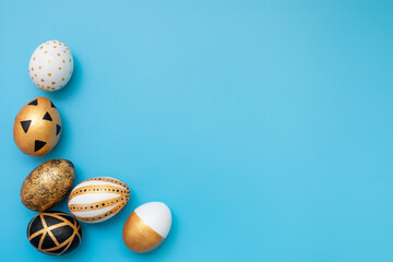 Golden, black, white easter eggs on blue background. Geometry. Minimal easter concept. View from above. Easter card with copy space for text.