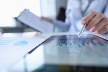 Female hand pointing with stylus to chart on tablet closeup