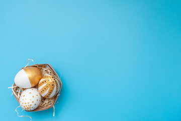 Golden, black, white easter eggs on blue background. Geometry. Minimal easter concept. View from above. Easter card with copy space for text.