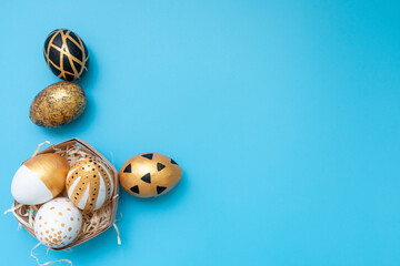 Golden, black, white easter eggs on blue background. Geometry. Minimal easter concept. View from above. Easter card with copy space for text.