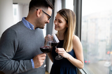 Cheerful happy couple in love drinking wine and having romantic date