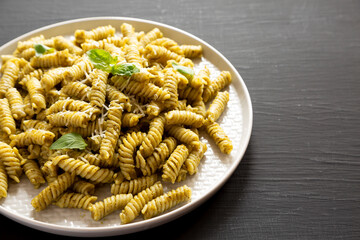 Homemade Pesto Twist Pasta on a plate on a black surface, side view. Copy space.