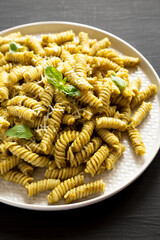Homemade Pesto Twist Pasta on a plate on a black background, side view. Close-up.