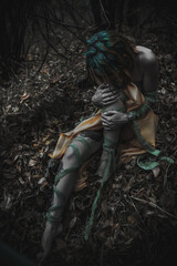 dead girl in autumn foliage wearing green and yellow robes