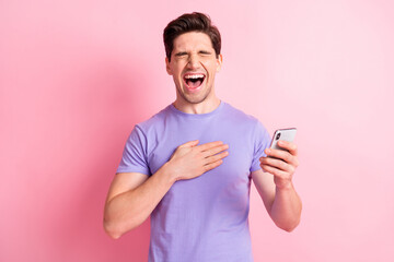 Portrait of attractive cheerful overjoyed guy using gadget app laughing having fun isolated over pink pastel color background