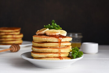 Homemade pancakes with banana and syrup for breakfast on the kitchen table.