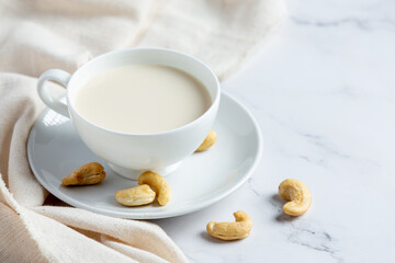 Obraz na płótnie Canvas Vegan cashew milk in glass with cashews nuts on marble background