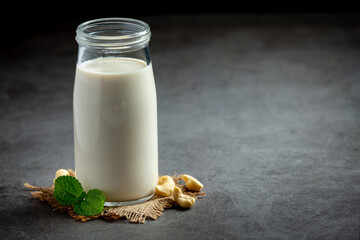 Vegan cashew milk in glass with cashews nuts on dark background