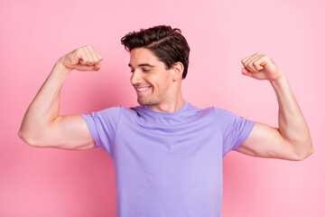 Portrait of nice attractive cheery fit guy demonstrating muscles isolated over pink pastel color background