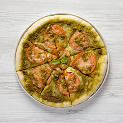 Homemade Pesto Pizza with Fresh Tomatoes and Mozzarella on a white wooden background, top view. Flat lay, overhead, from above.