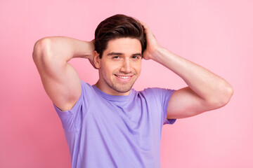 Portrait of attractive cheerful well-groomed guy touching coiffure isolated over pink pastel color...
