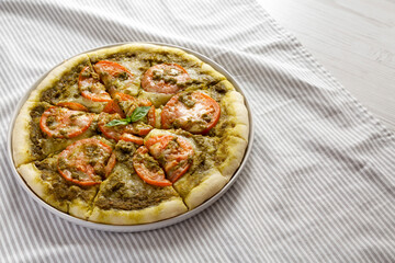 Homemade Pesto Pizza with Fresh Tomatoes and Mozzarella on cloth, side view. Copy space.