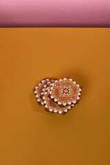 Vintage marquetery coasters with brown and beige colors. An eclectic oriental pattern made from mosaic wood on an ochre table and a pink background. Vertical shot