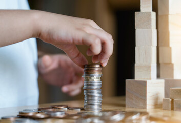 Kid hand stacking sterling pound coin and pennies nickels on wooden table with copy space, Financial planing for New Year resolution or saving money for business or life in future