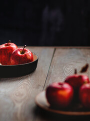 Fresh red apples on a plate on a wooden background. Red apples on a dark background. Selective focus