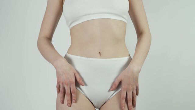 Woman in white panties posing in front of mirror, anti-cellulite cosmetics