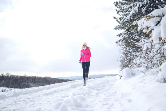 A woman runs in the snow in the winter mountains. Sports, fitness - inspiration and motivation. Woman jogging outdoors. High quality photo.