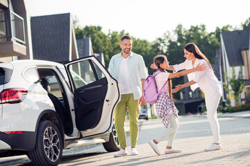 Photo portrait of father opening car door for daughter to come out and hug mother outdoors on street in summer