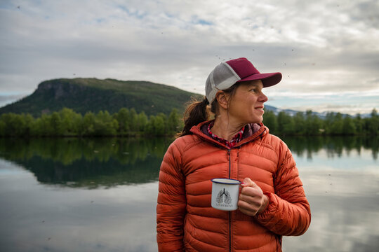Smiling woman with mug at lake