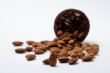 Almonds on a white background. Isolated almonds. Roasted almonds spilled out of the basket