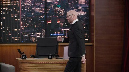 ZOOM IN Late-night talk show host entering studio, greeting audience and performing his monologue, looking into camera. TV broadcast style show. Shot with RED cinema camera