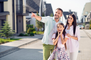 Photo of happy cheerful excited smiling family outside dad point finger copyspace mom and child girl look copyspace