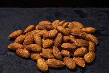 Almonds on a black background. Isolated almonds. Small pile of roasted almonds