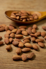Almonds on a wooden background. Isolated almonds. Roasted almonds in a wooden spoon