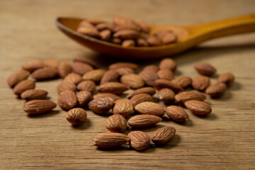Almonds on a wooden background. Isolated almonds. Roasted almonds in a wooden spoon