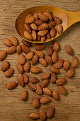 Almonds on a wooden background. Isolated almonds. Roasted almonds in a wooden spoon